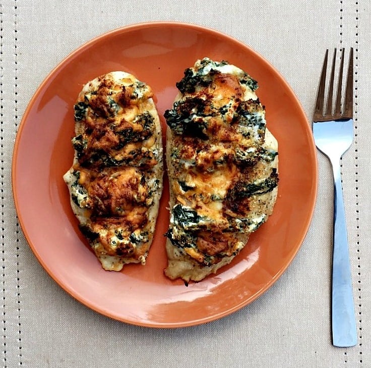 spinach and cream cheese stuffed chicken on an orange plate