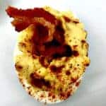 close up of bacon deviled egg on a white plate