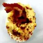 close up of bacon deviled egg on a white plate