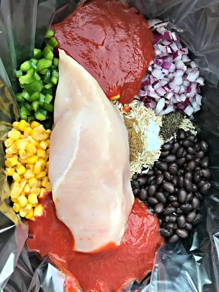 raw chicken breast, seasonings and veggies in a slow-cooker
