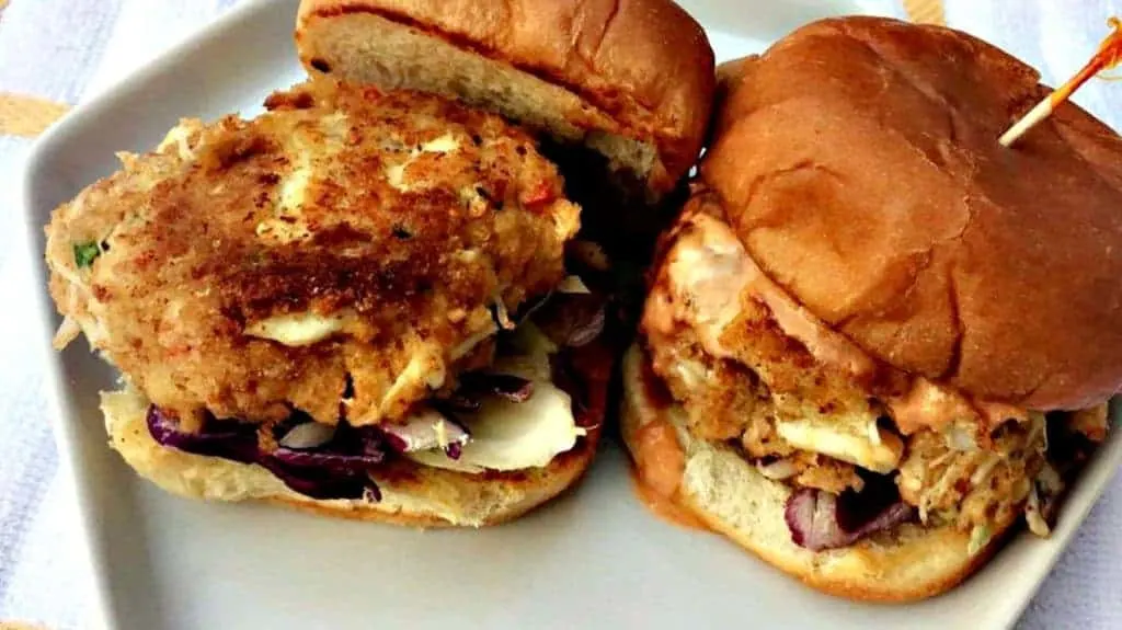 Crab Cake Sliders Crab Cake on a slider bun with Chipotle Mayo on a white plate