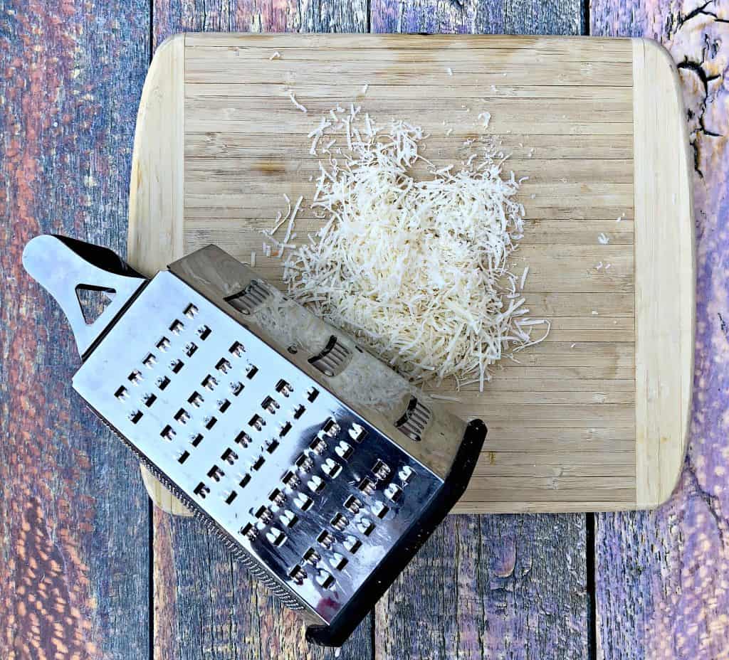 parmesan cheese with a cheese grater on a cutting board