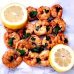 spicy smoky shrimp on a white surface with sliced lemons