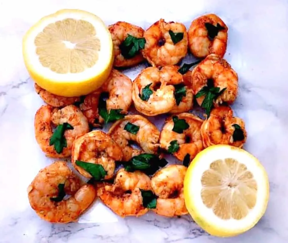 spicy smoky shrimp on a white surface with sliced lemons