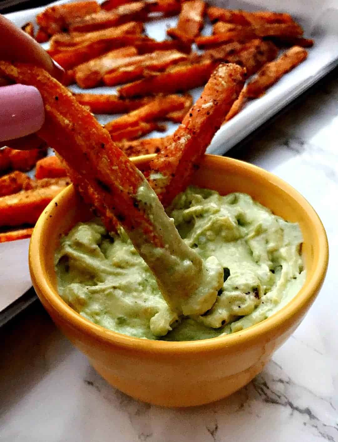 bowl of avocado garlic aioli with sweet potato fries