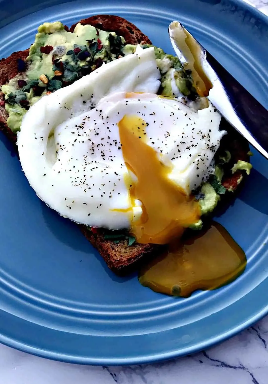 avocado cilantro lime toast with a poached egg on a plate