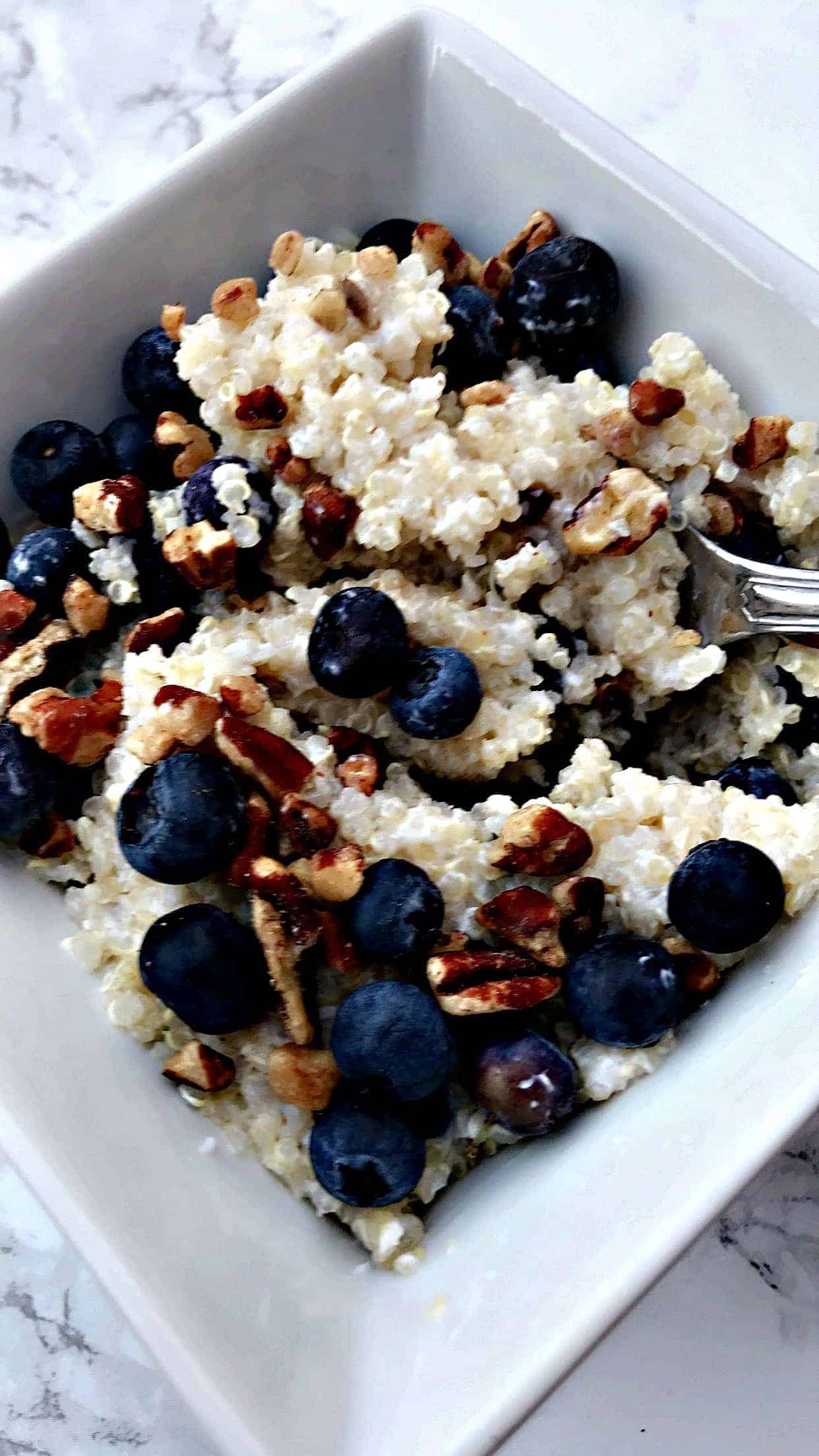 blueberry quinoa breakfast bowl with pecans in a white bowl