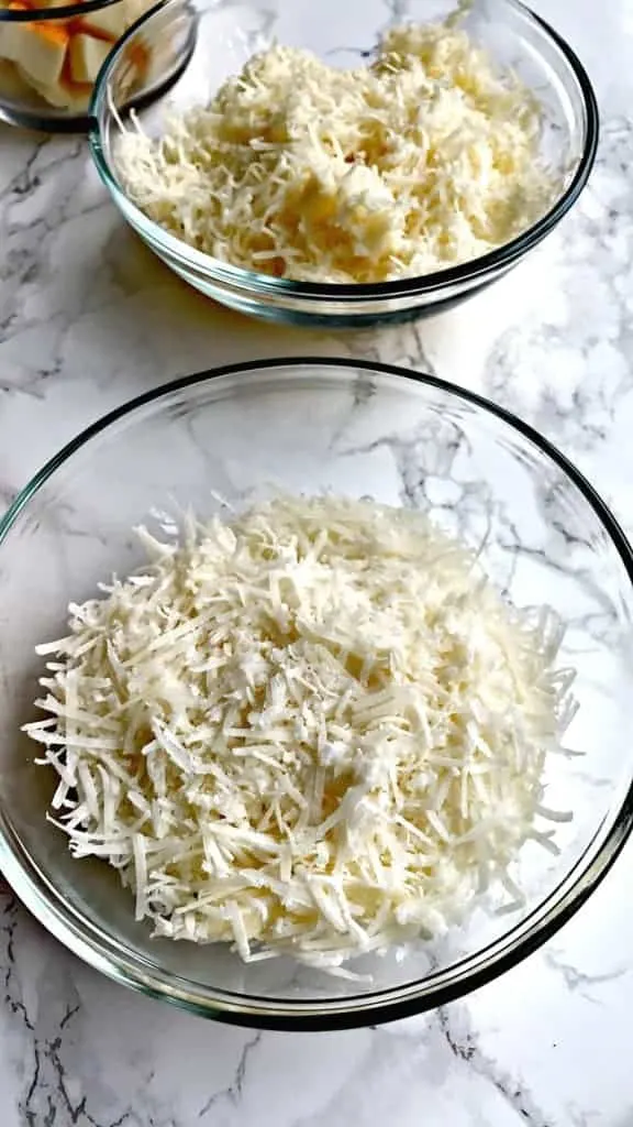 2 glass bowls containing shredded cheeses