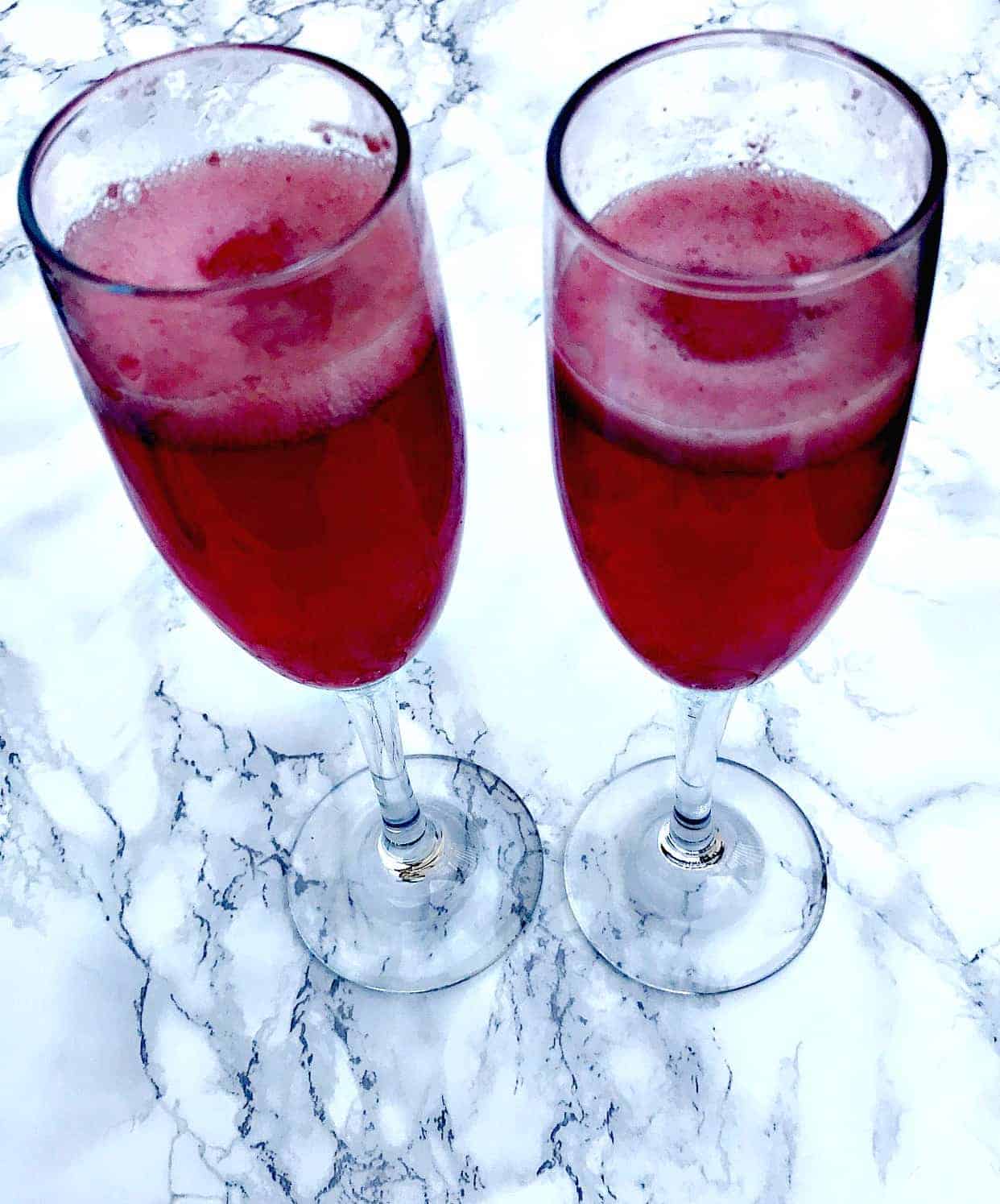2 champagne flutes filled with raspberry sorbet mimosas