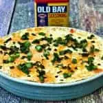Hot Cream Cheese Old Bay Seafood Crab Dip in a baking dish and a container of old bay seasoning