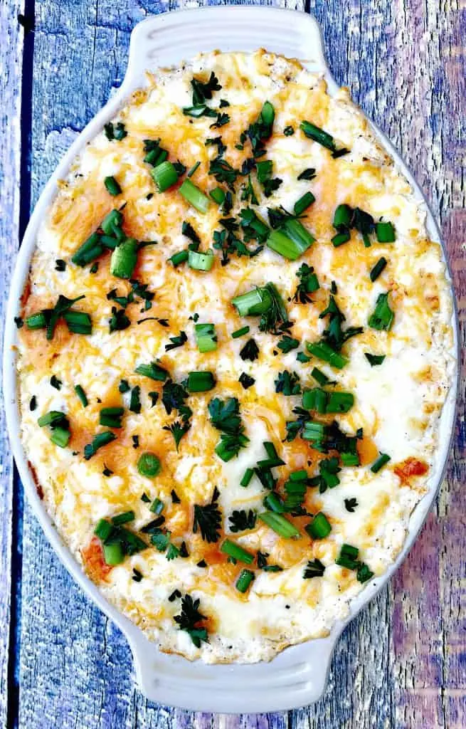 hot crab dip in a baking dish with green onions