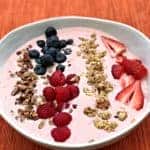 almond butter berry power protein smoothie topped with granola, blueberries, raspberries, and sliced strawberries in a white bowl