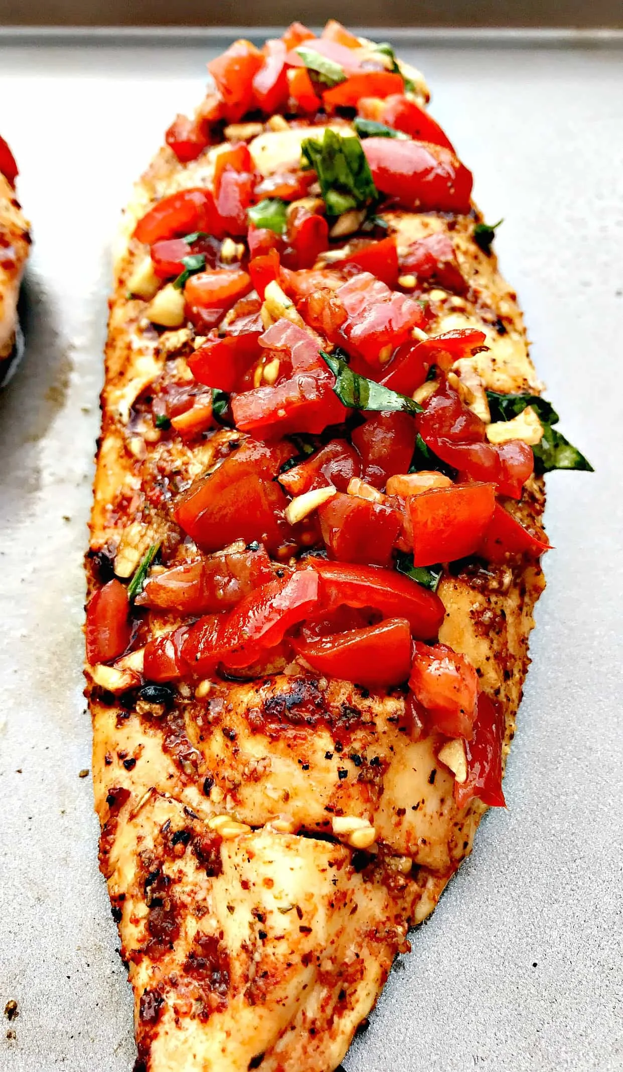 close up of bruschetta stuffed chicken on a baking sheet