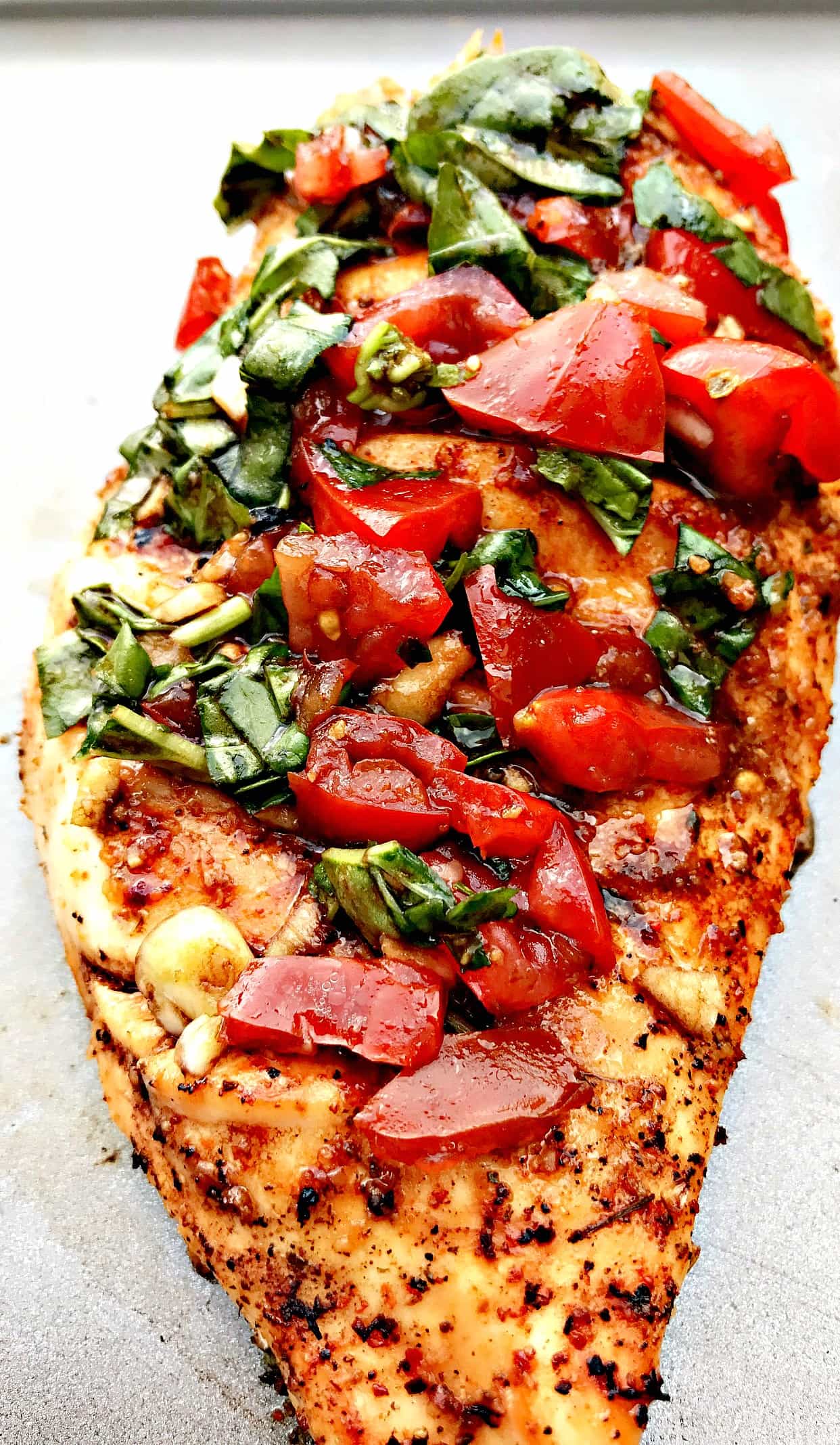 close up of bruschetta stuffed chicken on a baking sheet