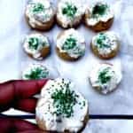 a square glass baking dish with 9 sugar cookies with white frosting and green sprinkles