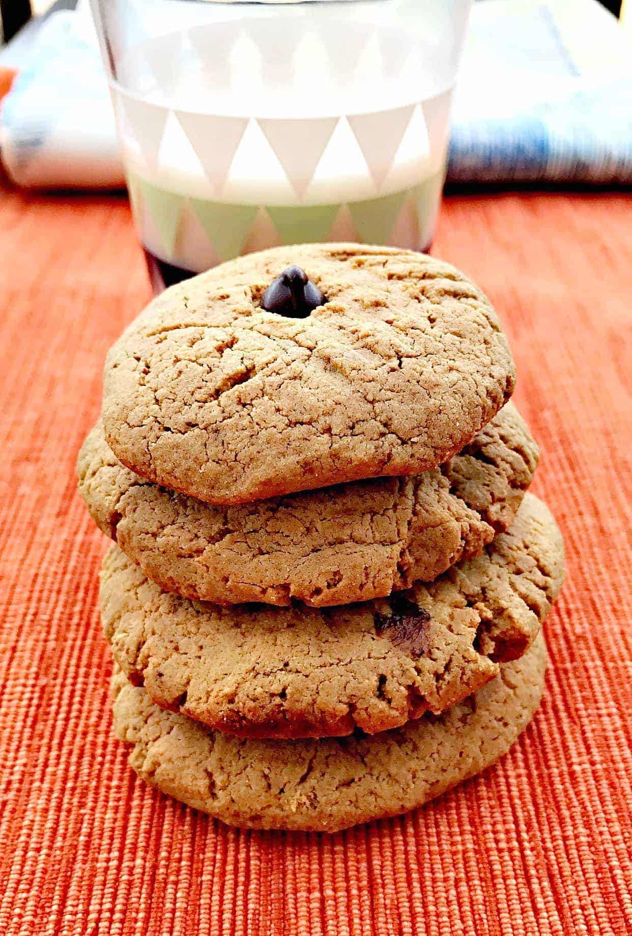 4 peanut butter dark chocolate chip protein cookies stacked in front of glass of milk