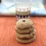 4 peanut butter dark chocolate chip protein cookies stacked in front of glass of milk