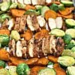 sliced chicken breasts, sweet potatoes, brussels sprouts on a baking sheet