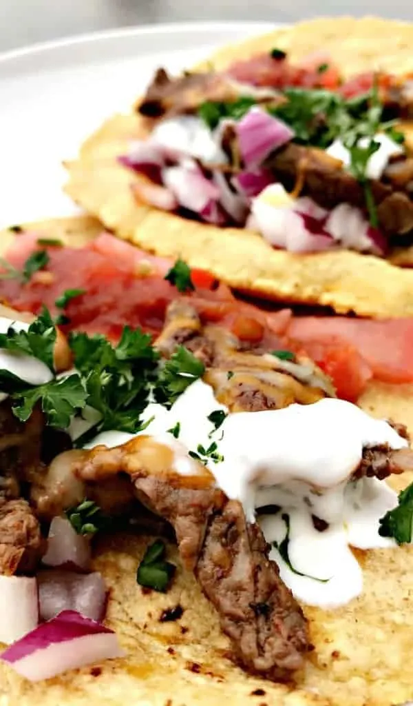 close up Instant Pot 10-Minute Steak Tacos (carne asada) with sour cream and tomatoes