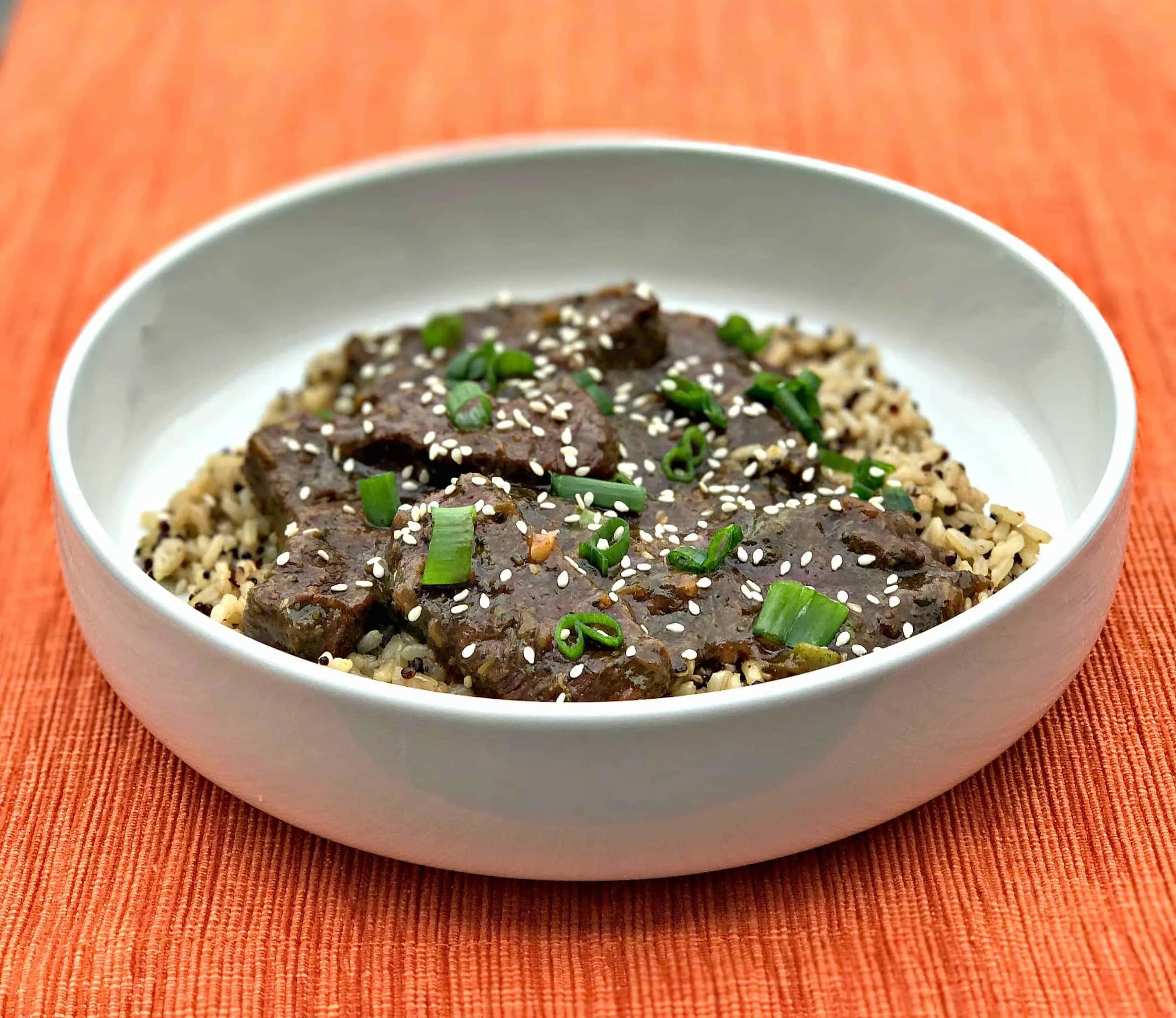 mongolian beef, quinoa and brown rice in a white bowl