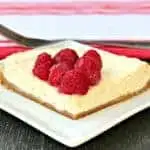 cheesecake topped with raspberries on a white plate