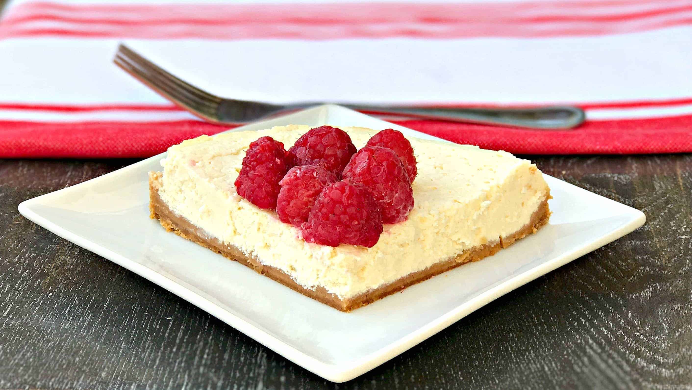 cheesecake topped with raspberries on a white plate