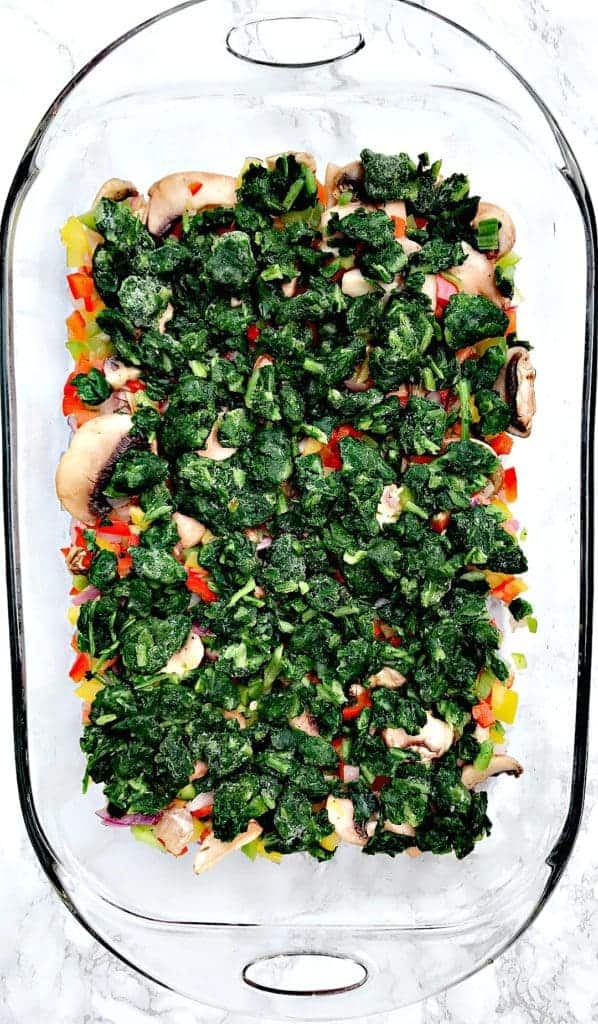 vegetable ingredients for Low-Carb Bacon, Egg, and Spinach Breakfast Casserole in a glass pan