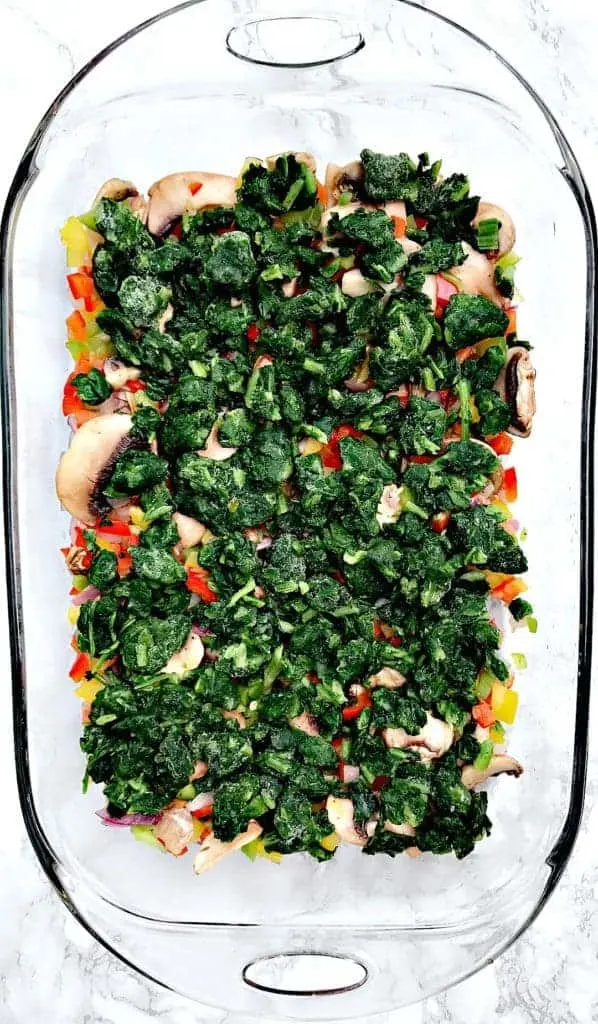 vegetable ingredients for Low-Carb Bacon, Egg, and Spinach Breakfast Casserole in a glass pan