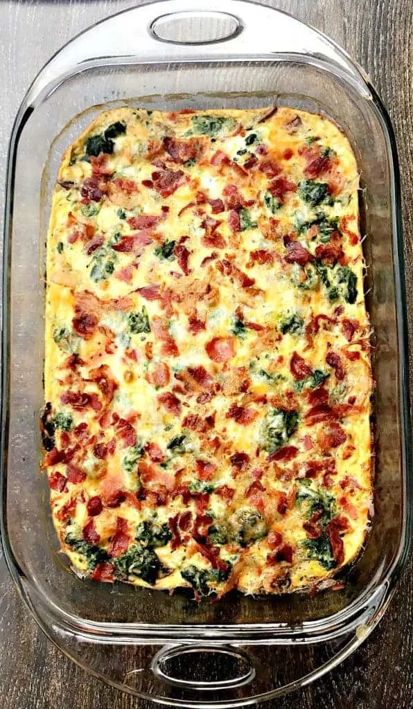 fully cooked Low-Carb Bacon, Egg, and Spinach Breakfast Casserole in a glass pan on a brown surface