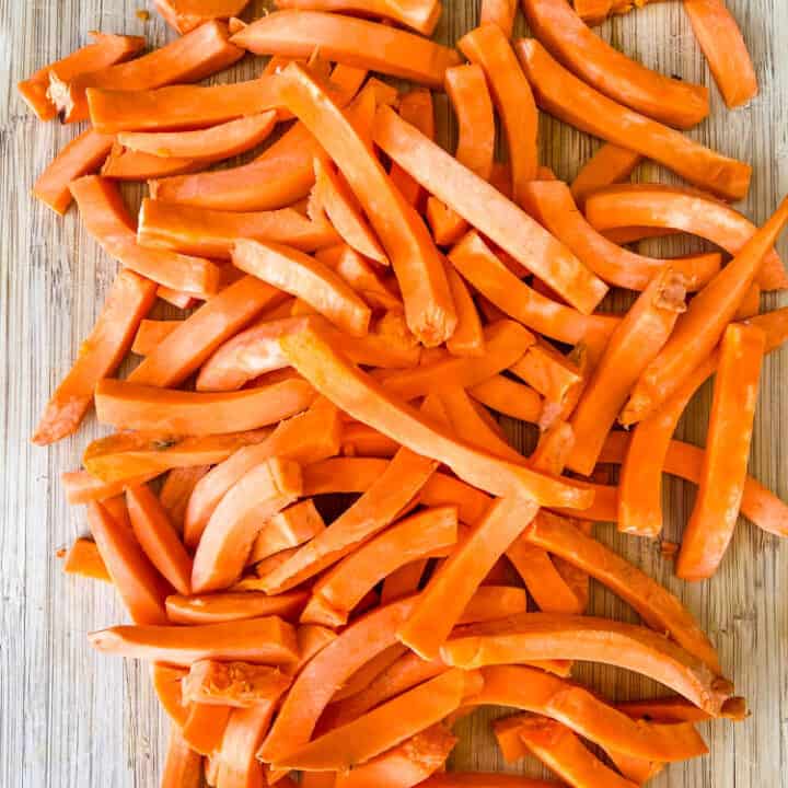 raw sweet potatoes sliced on a cutting board