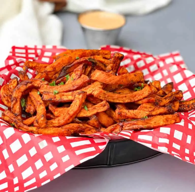 air fryer sweet potato fries in a basket with a red and white napkin