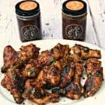 bbq ranch grilled chicken wings on a platter with 2 jars of bbq sauce in the background