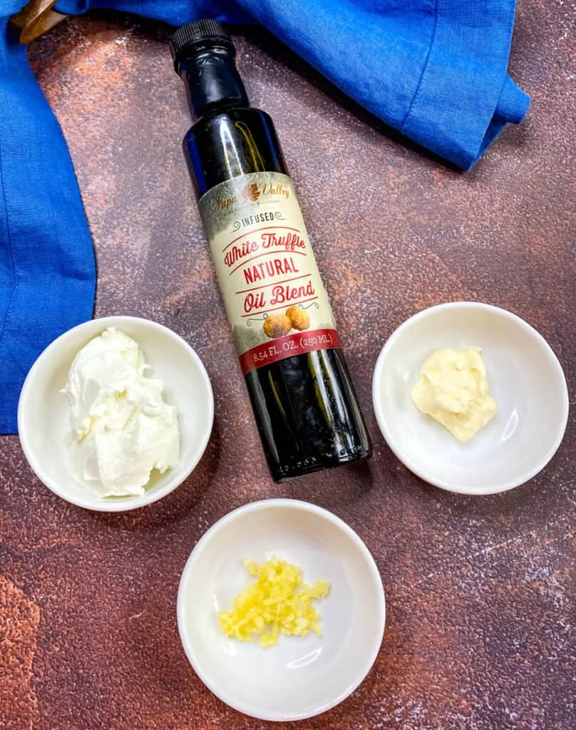 bottle of truffle oil, and containers of Greek yogurt, garlic, and mayo on a flat surface