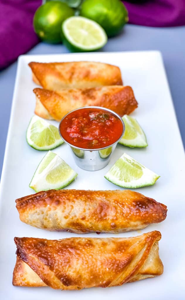 Air Fryer Beef Taco Fried Egg Rolls on a white plate with salsa and fresh limes