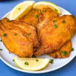 air fryer fried catfish on a white plate with fresh lemon