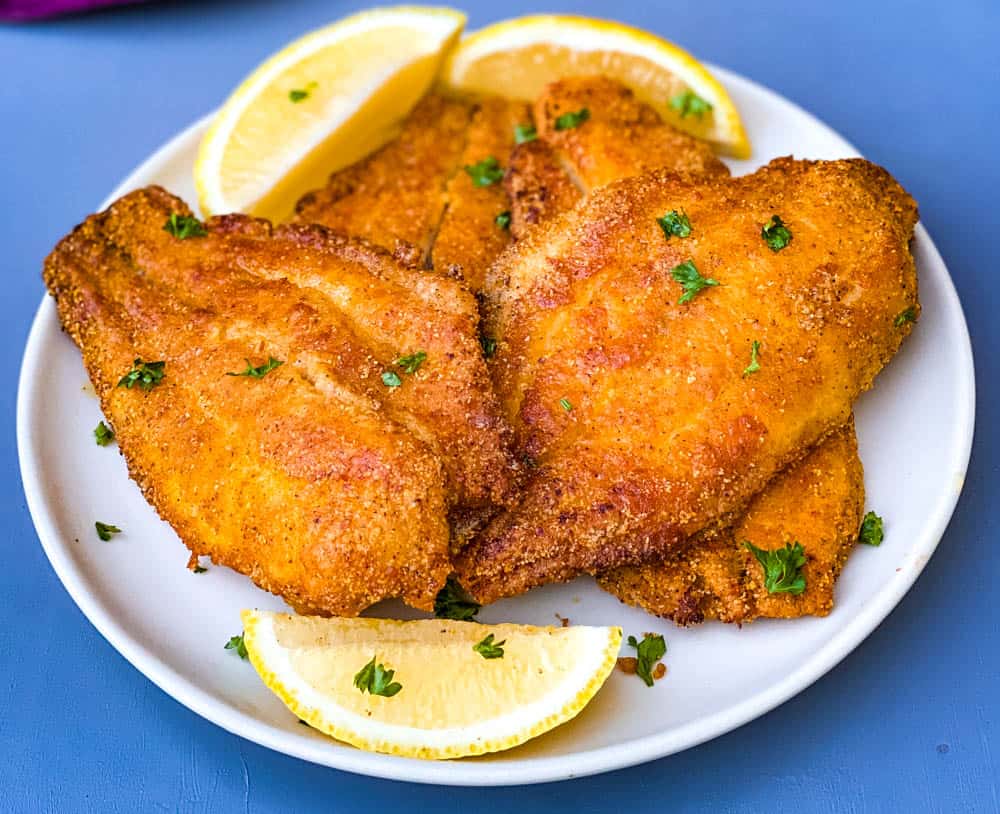 air fryer fried catfish on a white plate with fresh lemon