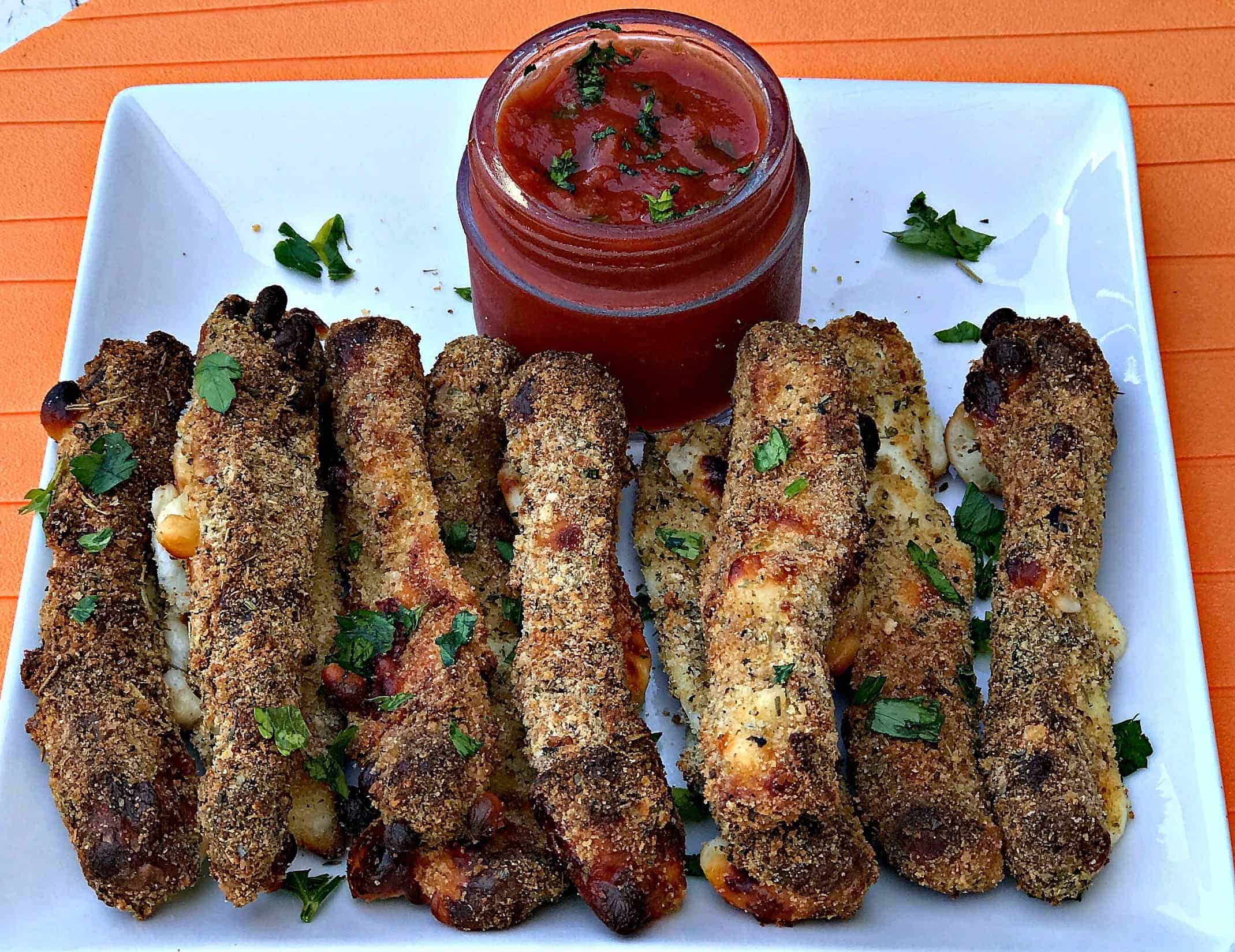 Air Fried Mozzarella Cheese Sticks on a white plate with a jar of marinara sauce