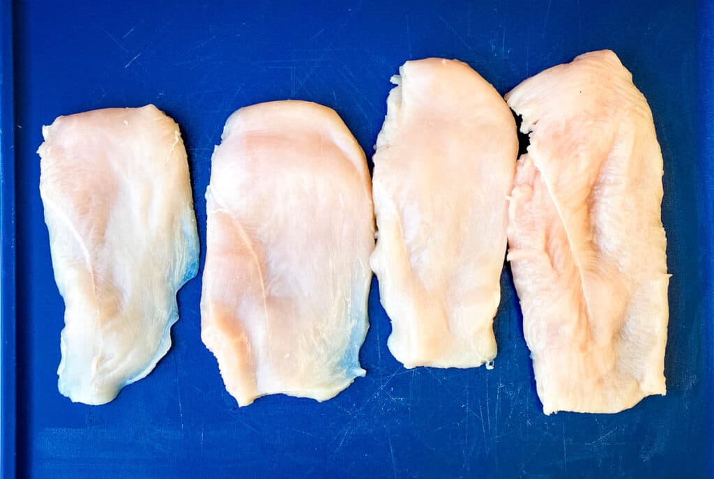 raw chicken breasts on a blue cutting board