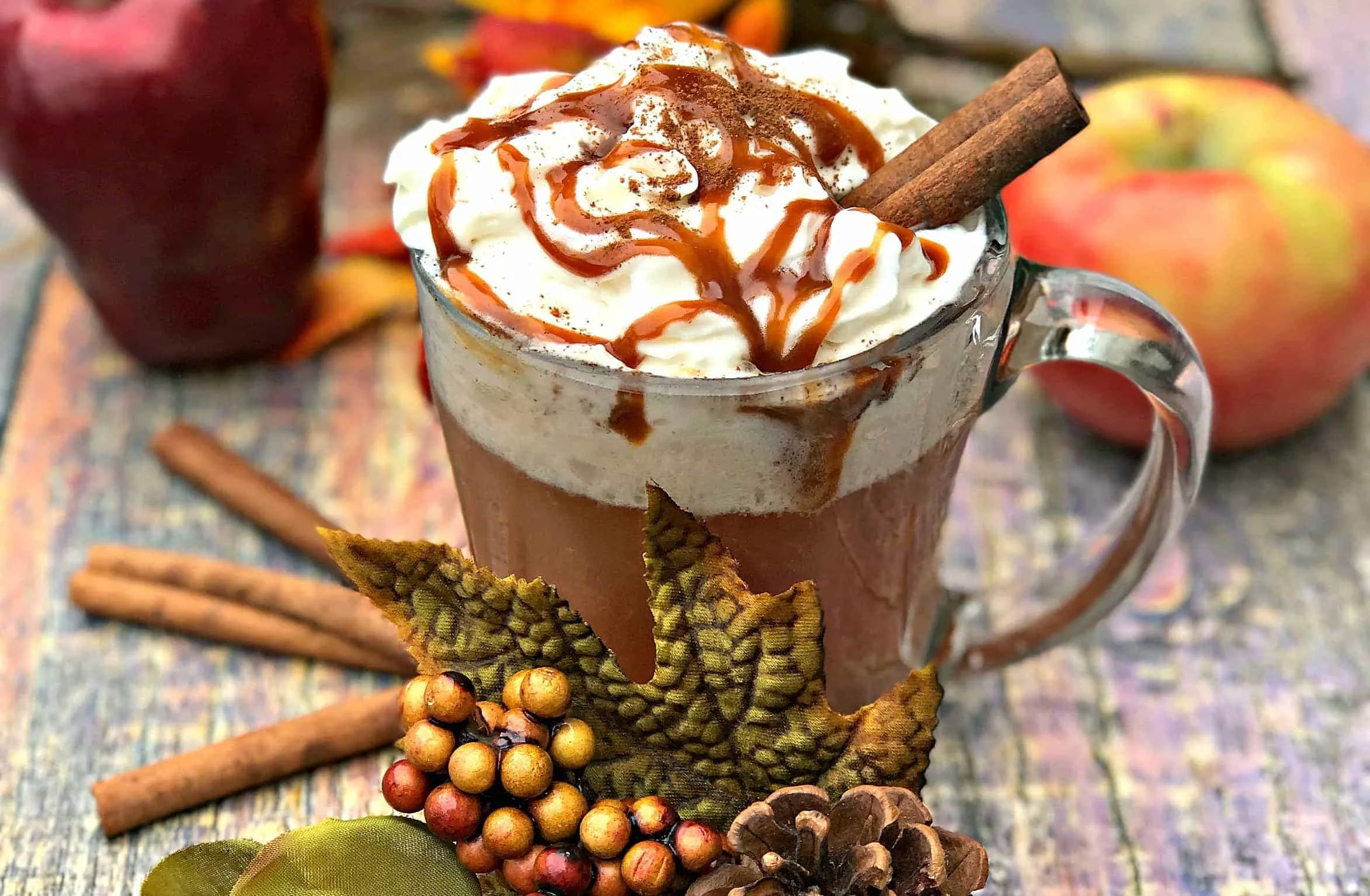 Skinny Copy-Cat Starbucks Caramel Apple Cider in a glass mug with fall decor surrounding the mug