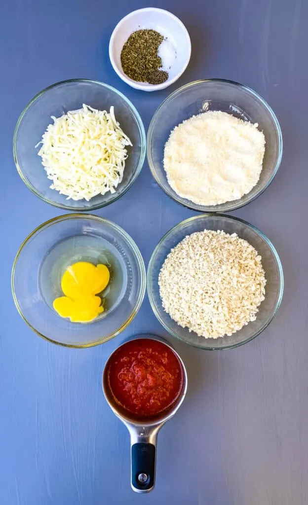 marinara sauce, breadcrumbs, an egg, mozzarella cheese, and parmesan cheese in separate bowls