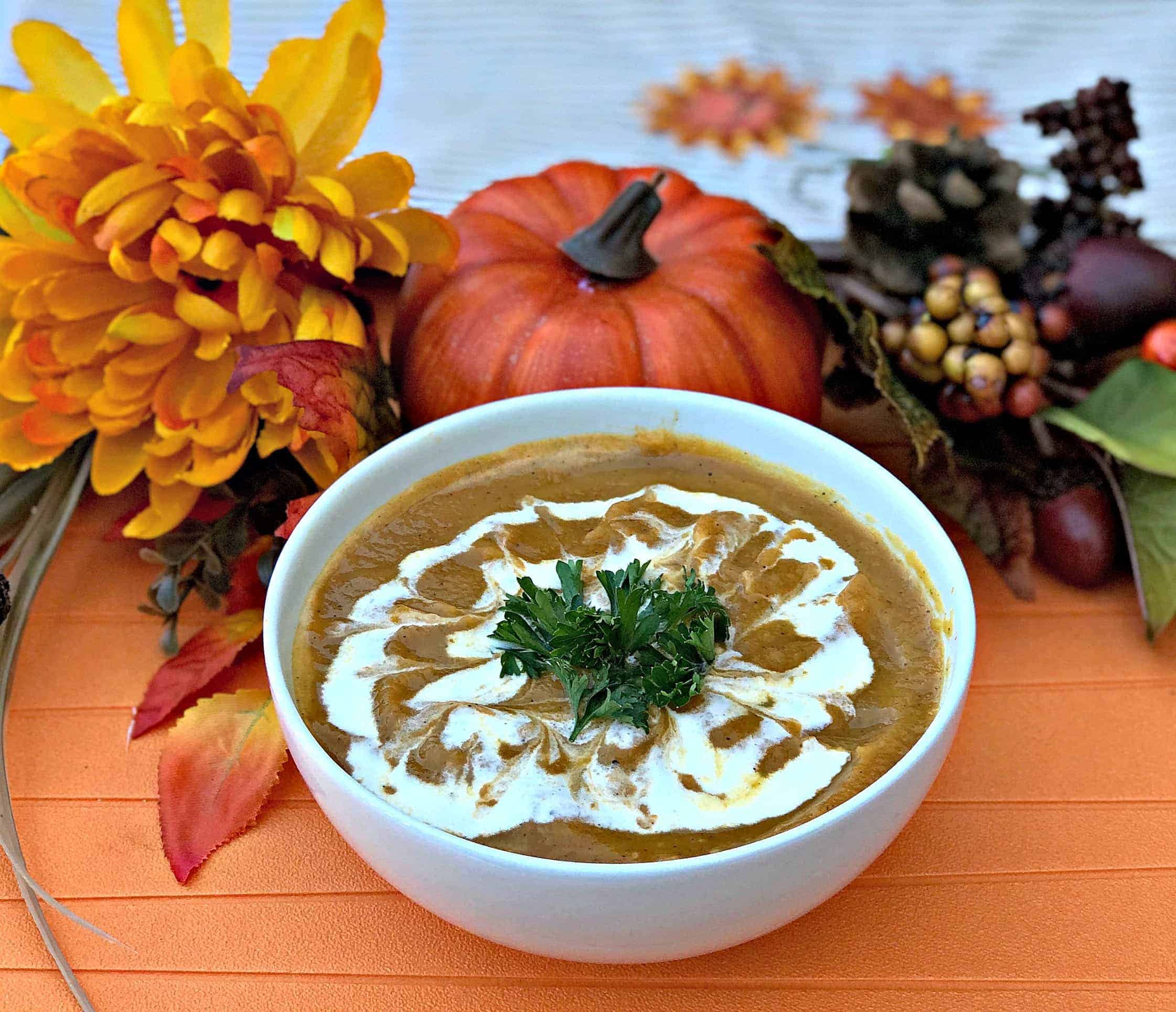 Instant Pot Pumpkin Spice and Sweet Potato Soup in a white bowl with fall decor in the background