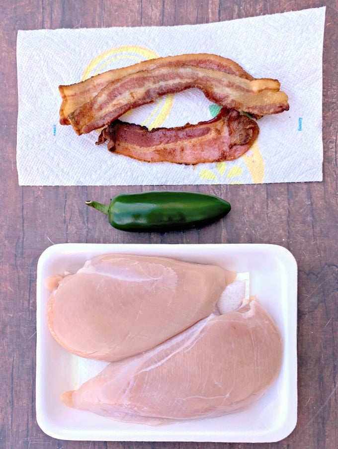 cooked bacon on a paper towel, fresh jalapeno, and raw chicken breasts