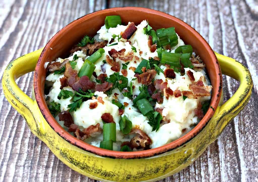 mashed potatoes in a yellow bowl with green onions