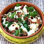 mashed potatoes in a yellow bowl with green onions