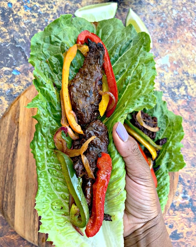 person holding keto low carb steak fajitas on a lettuce wrap