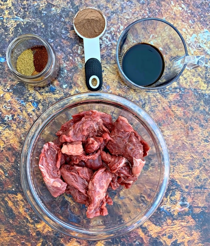 raw steak in a bowl with fajita seasoning and marinade