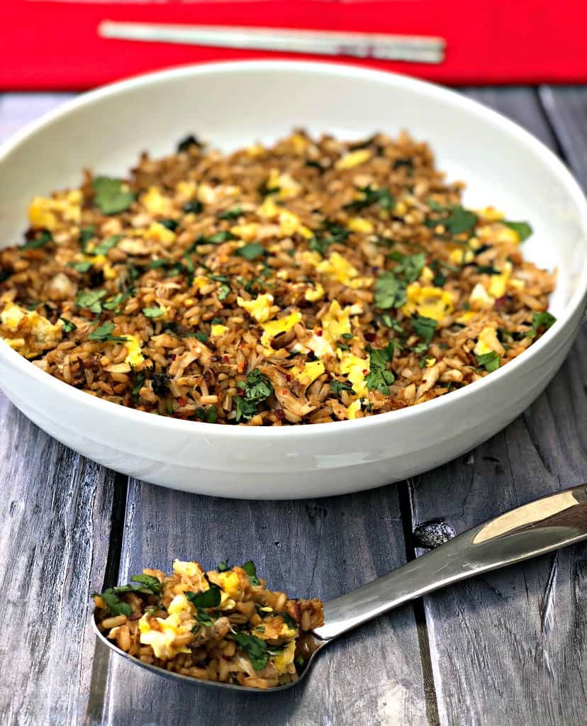 Air Fryer Crab Fried Rice in a white bowl with a large spoon of rice on a dark surface with a red napkin and chopsticks