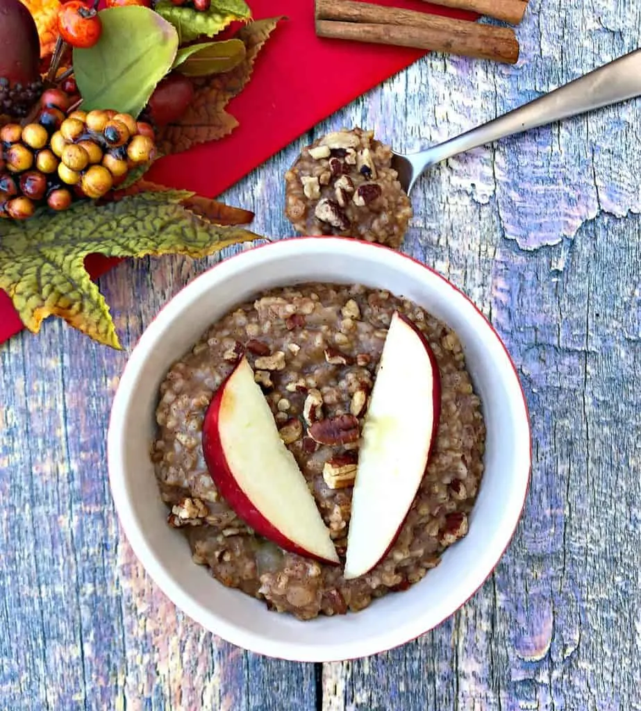 Instant Pot Apple Pie Steel Cut Oats in a red bowl with a fresh apple and red napkin