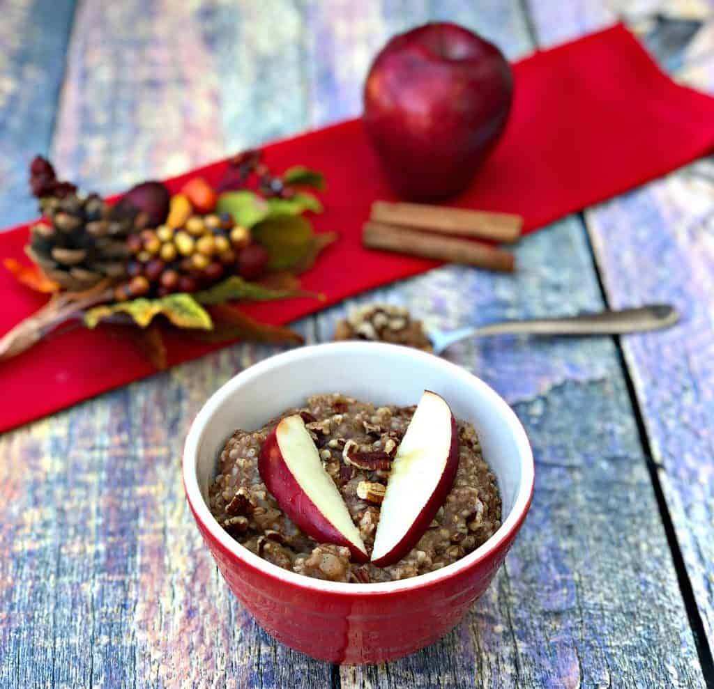 Instant Pot Apple Pie Steel Cut Oats in a red bowl with a fresh apple and red napkin