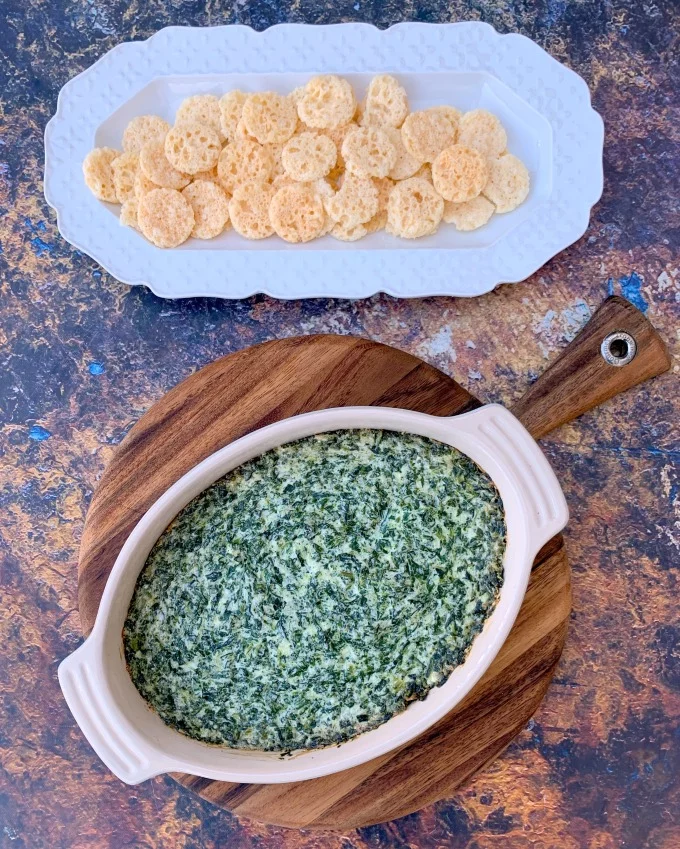 keto low carb spinach dip in a bowl with cheese crisps on a white plate